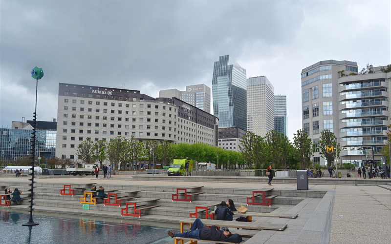11 - La Défense business district in Paris, France, featuring modern skyscrapers like the Allianz tower and public terraced seating near a water feature